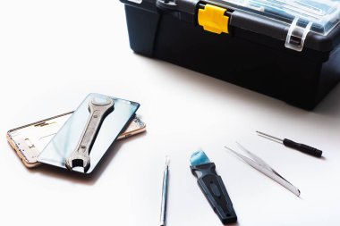 Beyaz arkaplandaki bazı bileşenleri tamir etmek veya değiştirmek için bozuk akıllı telefonu sökmenin düz bir görüntüsü vardı. Hasarlı bir cep telefonunu tamir ediyorum. İzole. Üst görünüm