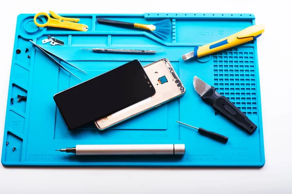 Bozuk akıllı telefonun bazı parçaları tamir etmek ya da değiştirmek için sökülmesinin düz bir görüntüsü vardı. Hasarlı bir cep telefonunu tamir ediyorum. Akıllı Telefon Tamir Aletleri. Üst görünüm