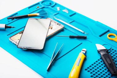 Bozuk akıllı telefonun bazı parçaları tamir etmek ya da değiştirmek için sökülmesinin düz bir görüntüsü vardı. Hasarlı bir cep telefonunu tamir ediyorum. Akıllı Telefon Tamir Aletleri. Üst görünüm