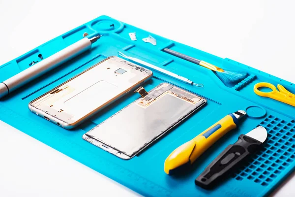 Bozuk akıllı telefonun bazı parçaları tamir etmek ya da değiştirmek için sökülmesinin düz bir görüntüsü vardı. Hasarlı bir cep telefonunu tamir ediyorum. Akıllı Telefon Tamir Aletleri. Üst görünüm