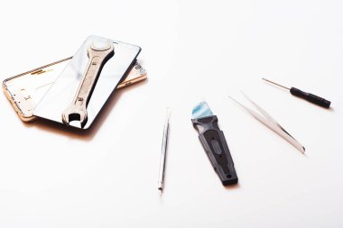 Beyaz arkaplandaki bazı bileşenleri tamir etmek veya değiştirmek için bozuk akıllı telefonu sökmenin düz bir görüntüsü vardı. Hasarlı bir cep telefonunu tamir ediyorum. İzole. Üst görünüm