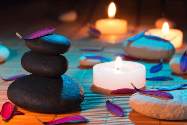 Witte en zwarte stenen, paarse bloemblaadjes en kaarsen — Stockfoto