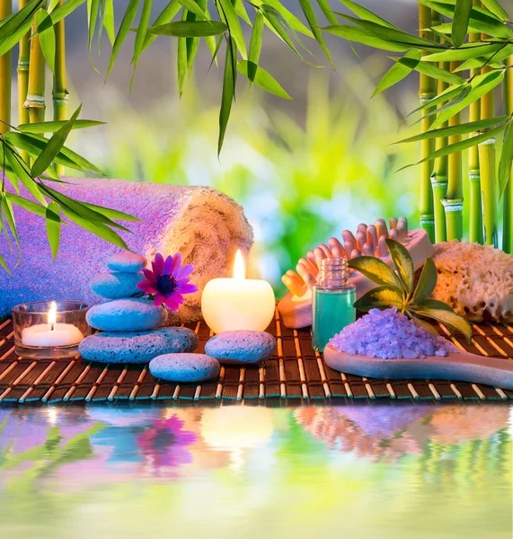 Массаж в бамбуковом саду с фиолетовыми цветами, свечами — стоковое фото