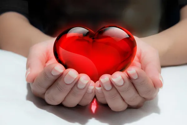 Corazón de vidrio en la mano del corazón — Foto de Stock