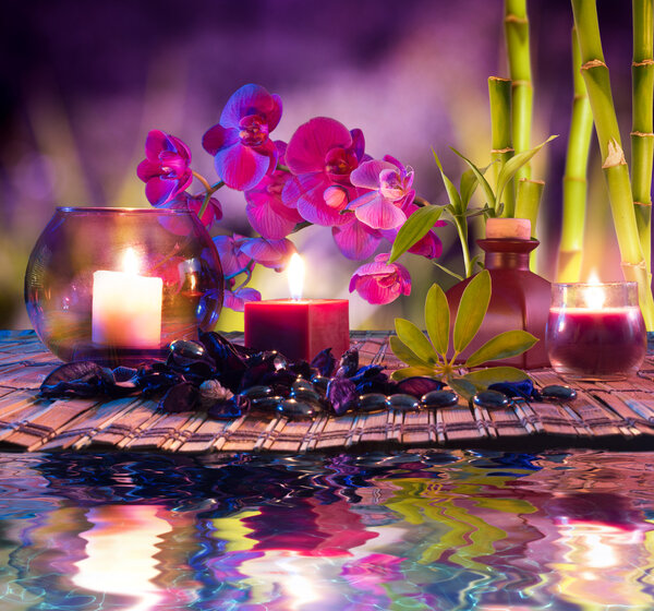 Violet composition - candles, oil, orchids and bamboo on water