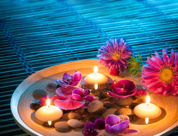 Plato spa con velas flotantes, margaritas, orquídea en la estera — Foto de Stock