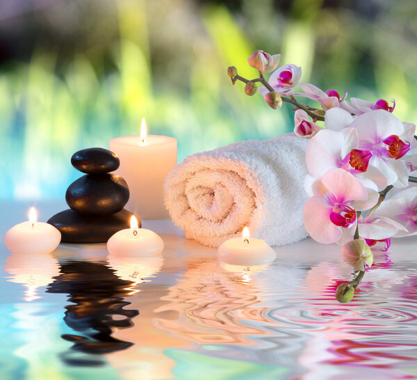 Preparation for massage in white with towels, stones, in garden