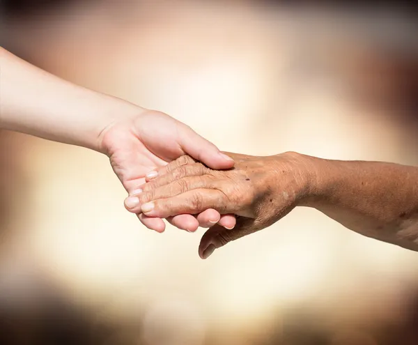 Aid concept - problems elderly - hands of young and senior — Stock Photo, Image