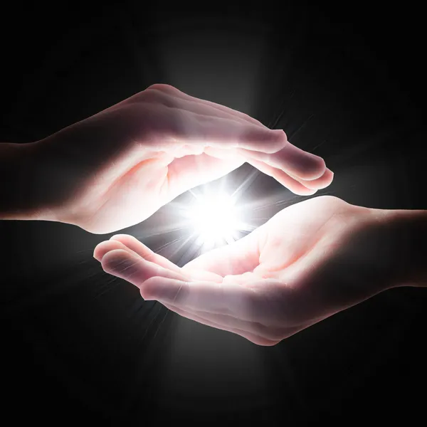 Cross light in the darkness in your hands — Stock Photo, Image