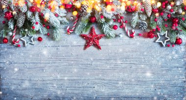 Mavi tahta üzerinde fidan dalları ve karlı Noel süsü