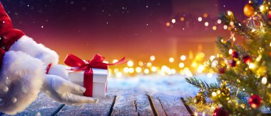 Noel Baba, Noel ağacının altına hediyesini gece soyut ışıklarıyla koyuyor.