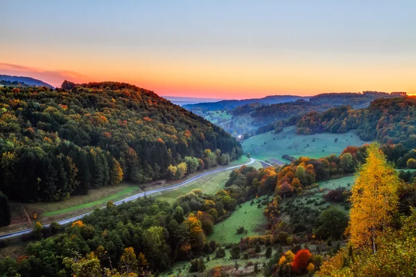 Paesaggio idilliaco autunnale con colorati aranci dorati vicino a una bella strada di campagna nelle montagne rocciose del Giura in Baviera, Germania. Tramonto in autunno con un meraviglioso cielo limpido nella campagna rurale . — Foto Stock