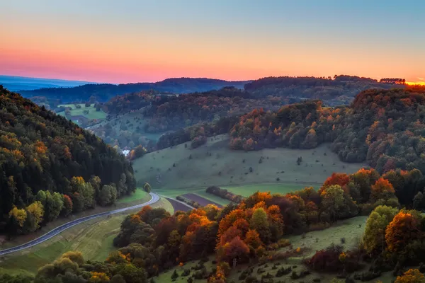 Paysage d'automne idyllique avec des arbres dorés orange colorés près d'une belle route de campagne dans les montagnes rocheuses du Jura de Bavière, en Allemagne. Coucher de soleil à l'automne avec un ciel clair magnifique dans la campagne . — Photo