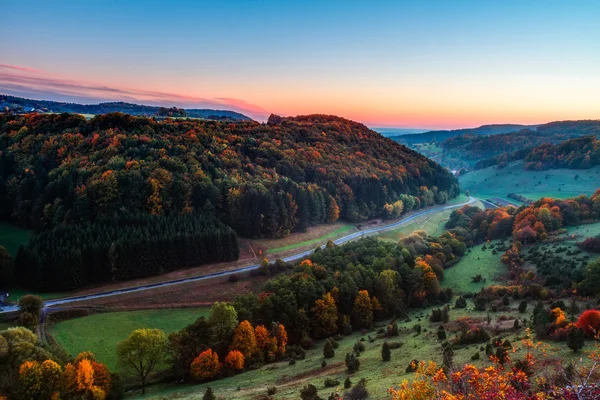 Paesaggio idilliaco autunnale con colorati aranci dorati vicino a una bella strada di campagna nelle montagne rocciose del Giura in Baviera, Germania. Tramonto in autunno con un meraviglioso cielo limpido nella campagna rurale . — Foto Stock