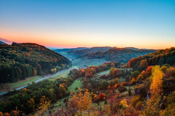 Idyllische herfst landschap met kleurrijke oranje gouden bomen in de buurt van een mooie landweg in de rotsachtige bergen van de jura van Beieren, Duitsland. zonsondergang in de herfst met een prachtige heldere hemel in het platteland. — Stockfoto