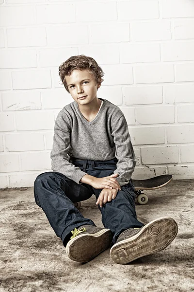 Крутой мальчик, сидящий на коньках — стоковое фото