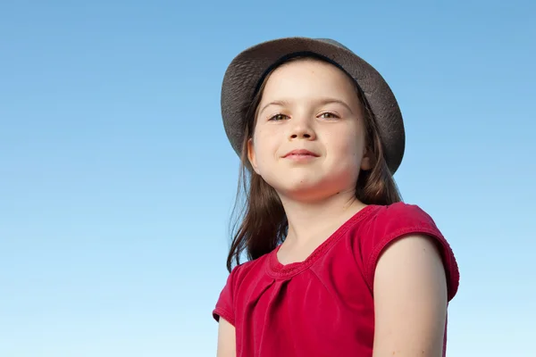 Schattig klein meisje buiten het dragen van een rode shirt en een hoed — Stockfoto