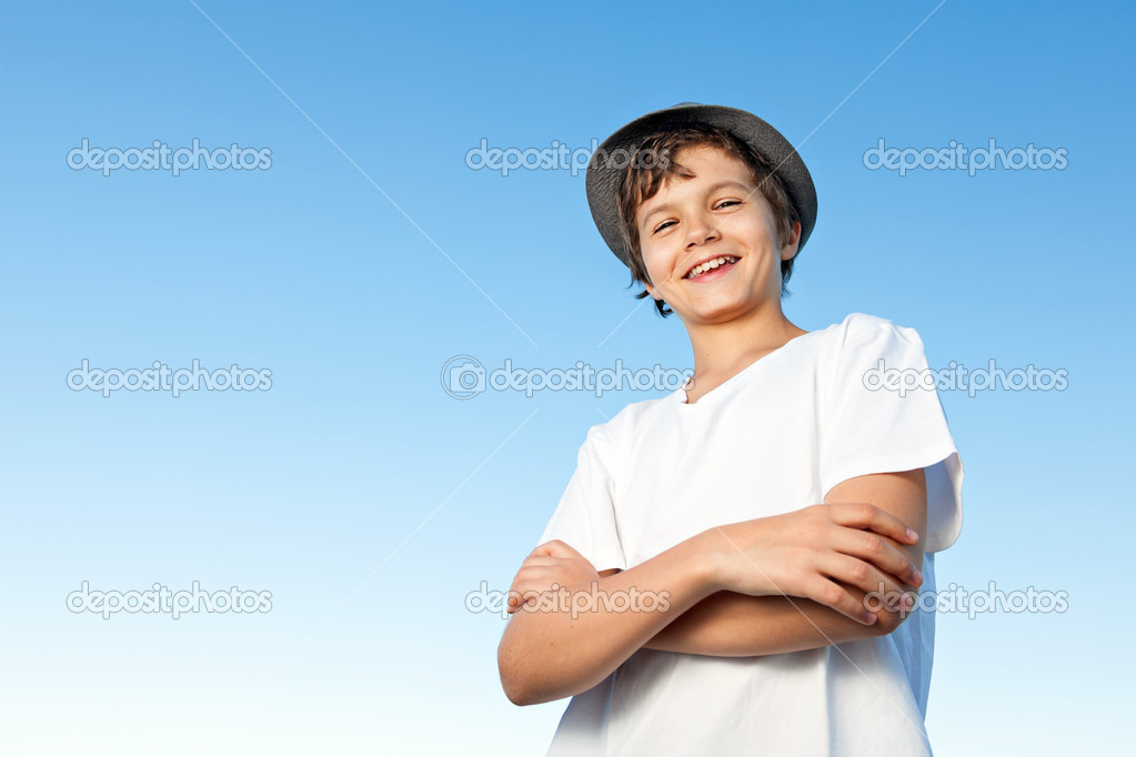 Handsome teenage boy standing outside against a blue sky