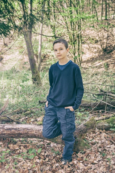 Bom menino olhando de pé em uma floresta — Fotografia de Stock