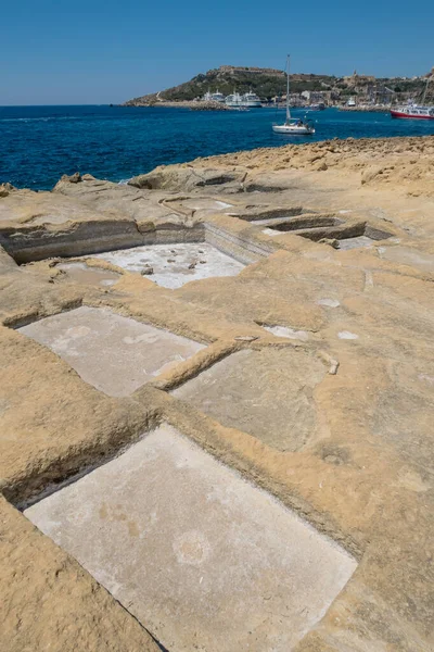 在一个阳光明媚的夏天 戈佐在马耳他海岸线上的一块石板上 船尾停泊着一艘船 图库图片