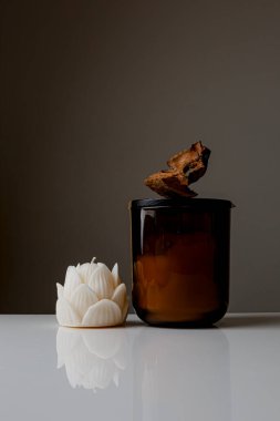 Cozy home and Spa concept. Hygge. Modern stylish and minimal round vase with dried lagurus grass, seashell candles and palm leaves in front of a grey wall.