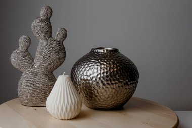 Cozy home and Spa concept. Hygge. Modern stylish and minimal round vase with dried lagurus grass, seashell candles and palm leaves in front of a grey wall.