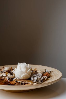 Cozy home interior decor, aromatic candles in glass glowingon white and grey background with natural oil, selective focus of fluffy bunny tail grass, brown jar, lotus flower candle, round matt ceramic