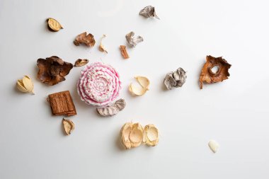 Small rose lotus candle in an transparent lotus shaped glass candle holder laying on glass mirrow white table. Christmas concept.