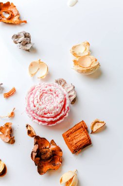 Small rose lotus candle in an transparent lotus shaped glass candle holder laying on glass mirrow white table. Christmas concept.