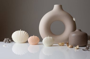 Ceramic pastel design round hole vases with seashell candles and soft aroma grass. Cozy home. Christmas decoration.