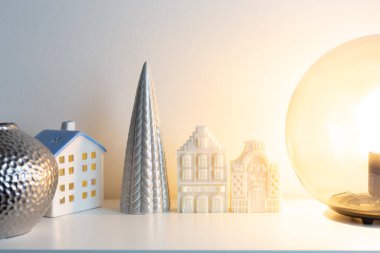 White candle dutch houses with ceramic christmas tree and glass round light lamp. Christmas home decorations. Happy holidays