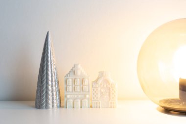 White candle dutch houses with ceramic christmas tree and glass round light lamp. Christmas home decorations. Happy holidays