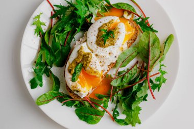 Avocado egg benedict with cream cheese Philadelphia. Poached eggs on healthy bread toast with hollandaise sauce. Cut egg. The yolk flows out. Green salad arugula leaves.