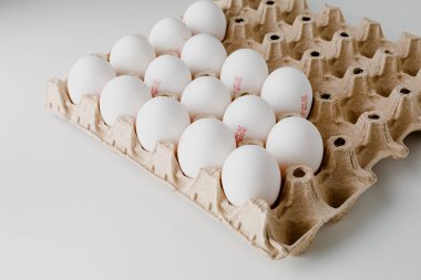 White eggs in brown carton on white with clipping path. Chicken eggs in tray.