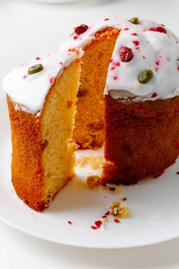 Easter muffin cake with pistachios and cranberry and easter decorations on a white plate. White background. Copy space.
