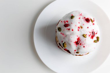 Blueberry muffin with whipped cream. Easter muffin cake with pistachios and cranberry and easter decorations on a white plate. Dragon lilac easter eggs. White background. Copy space.