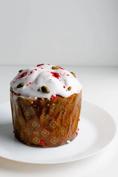 Blueberry muffin with whipped cream. Easter muffin cake with pistachios and cranberry and easter decorations on a white plate. Dragon lilac easter eggs. White background. Copy space.