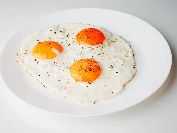 Three Fried Eggs Pepper Salt White Plate White Background — Stockfoto