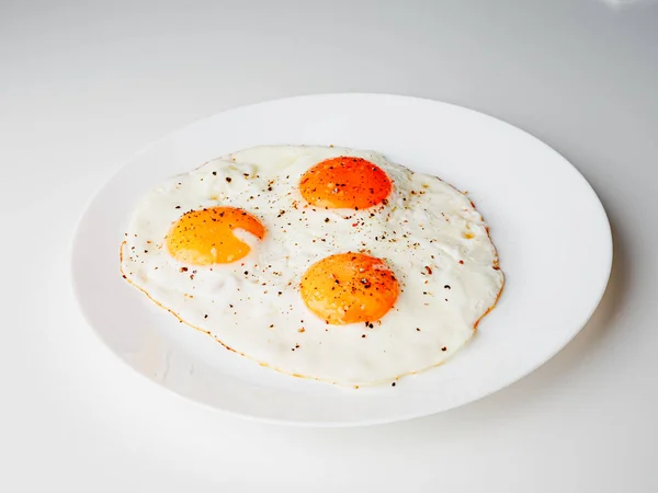 Three Fried Eggs Pepper Salt White Plate White Background — Stock fotografie