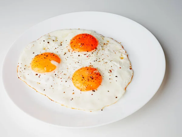 Three Fried Eggs Pepper Salt White Plate White Background — Stockfoto