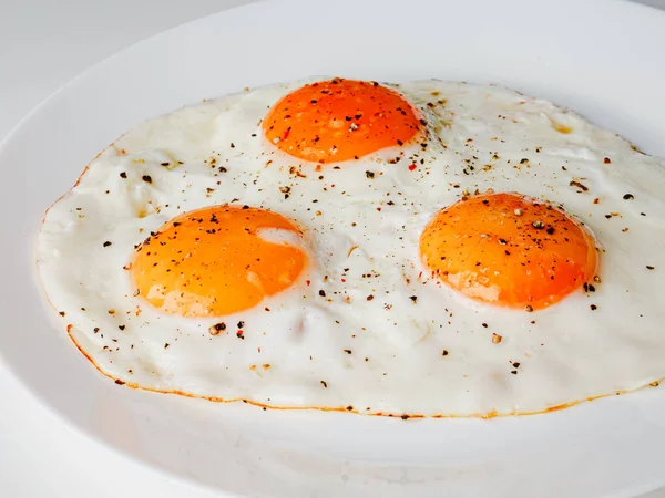 Three Fried Eggs Pepper Salt White Plate White Background — Stockfoto