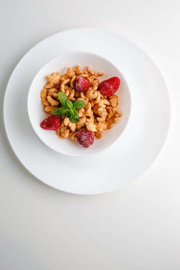Tasty corn flakes with strawberries and leaves of mint on white background. Breakfast. Cornflakes with berry and milk. Cereal flakes. Fresh healthy food. Morning meal.