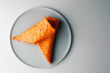 Shawarma sandwich gyro- fresh roll of thin lavash (pita bread) filled with grilled meat, mushrooms, cheese, cabbage, carrots, sauce, green. Traditional Eastern snack. On dark grey background