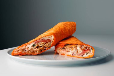 Shawarma sandwich gyro- fresh roll of thin lavash (pita bread) filled with grilled meat, mushrooms, cheese, cabbage, carrots, sauce, green. Traditional Eastern snack. On dark grey background