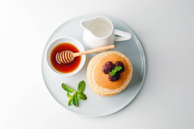 American pancakes with fresh blueberry, raspberry and honey. Healthy morning breakfast. Homemade American pancakes with Blackberries and golden honey. Healthy morning breakfast.