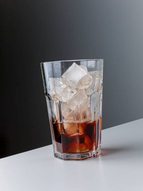 Cola with Ice Cubes. Glass of cola. Copy Space. Pour soft drink in glass with ice splash on dark background. glass of cola with ice isolated. Soft drink glass with ice splash on cool smoke background.