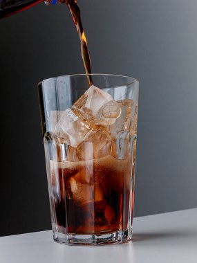Cola with Ice Cubes. Glass of cola. Copy Space. Pour soft drink in glass with ice splash on dark background. glass of cola with ice isolated. Soft drink glass with ice splash on cool smoke background.