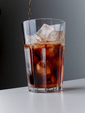 Cola with Ice Cubes. Glass of cola. Copy Space. Pour soft drink in glass with ice splash on dark background. glass of cola with ice isolated. Soft drink glass with ice splash on cool smoke background.