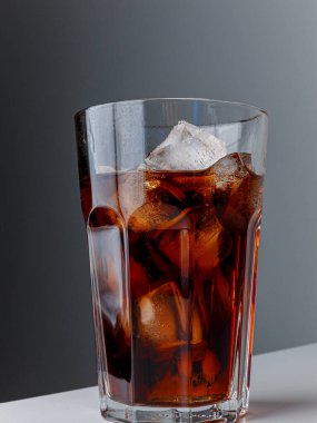 Cola with Ice Cubes. Glass of cola. Copy Space. Pour soft drink in glass with ice splash on dark background. glass of cola with ice isolated. Soft drink glass with ice splash on cool smoke background.