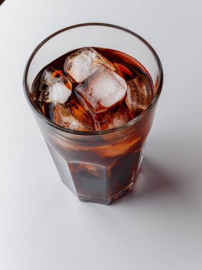 Cola with Ice Cubes. Glass of cola. Copy Space. Pour soft drink in glass with ice splash on dark background. glass of cola with ice isolated. Soft drink glass with ice splash on cool smoke background.